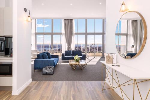 a living room with blue furniture and a mirror at Meriton Suites Bondi Junction in Sydney