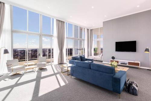 a living room with a blue couch and a tv at Meriton Suites Bondi Junction in Sydney