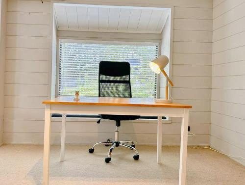 a desk with a lamp and a chair in a room at Orewa Motor Lodge in Orewa
