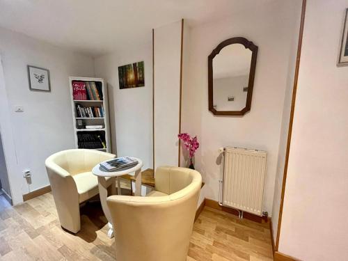 - un salon avec deux chaises, une table et un miroir dans l'établissement Gîte authentique avec terrasse couverte, 16 km de Gérardmer, 4 chambres, équipement bébé, Wi-Fi inclus - FR-1-589-231, à Aumontzey