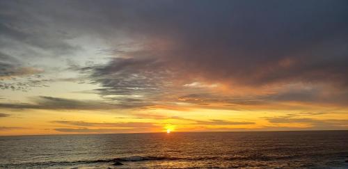 a sunset over the ocean with the sun setting at Cabañas Pozo Azul in El Quisco