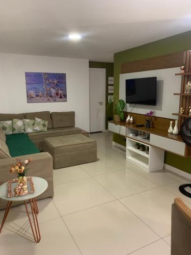 a living room with a couch and a tv at apartamento de frente para o mar com linda area de lazer in Arraial do Cabo