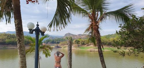 a woman in a bikini standing between two palm trees at Las Palmas - Espectacular casa a borde de lago con piscina in Prado