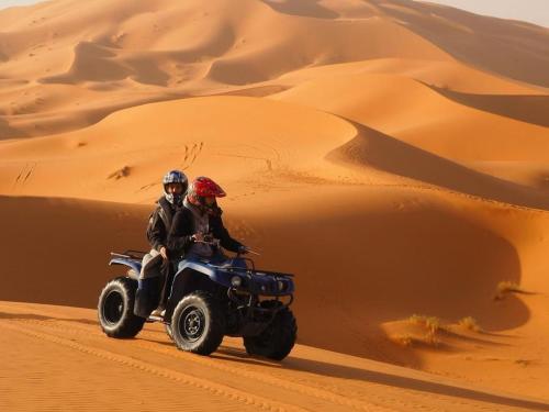two people riding a quad bike in the desert at Merzouga Best Luxury Camp in Merzouga