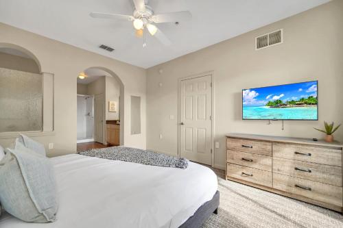 a bedroom with a white bed and a flat screen tv at 2BR Condo with Hot tub and pool, near Disney! in Orlando