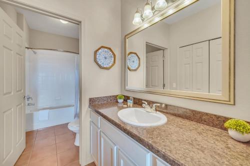 a bathroom with a sink and a mirror and a toilet at 2BR Condo with Hot tub and pool, near Disney! in Orlando