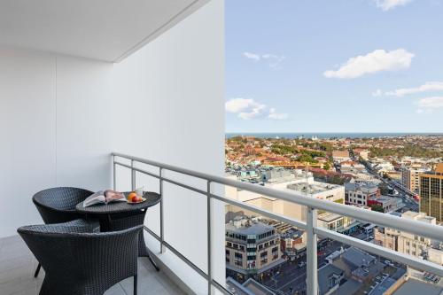 a balcony with two chairs and a view of a city at Meriton Suites Bondi Junction in Sydney