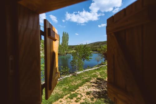 a view of a river from a wooden door at River huts Zrmanja in Obrovac