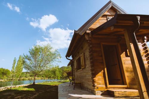 a log cabin with a porch and a lake at River huts Zrmanja in Obrovac