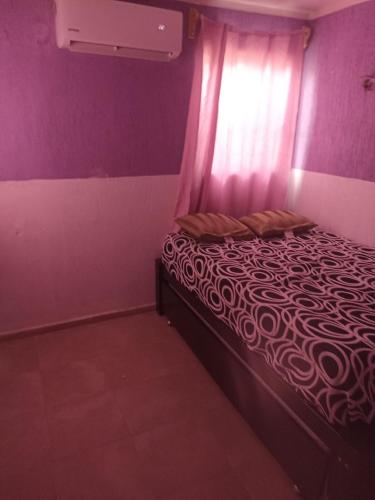 a bedroom with a bed with purple walls and a window at casa particular amueblada in Umán