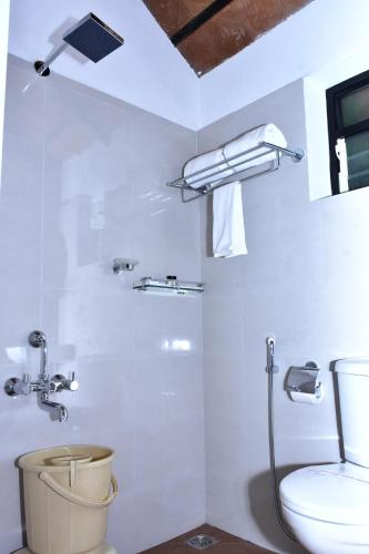 a white bathroom with a shower and a toilet at River Valley Retreat Coorg in Madikeri