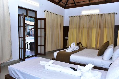 a hotel room with two beds and a balcony at River Valley Retreat Coorg in Madikeri