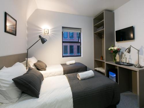 a bedroom with two beds and a desk and a window at Dancenter River Roding Ilford Inn London in Barking