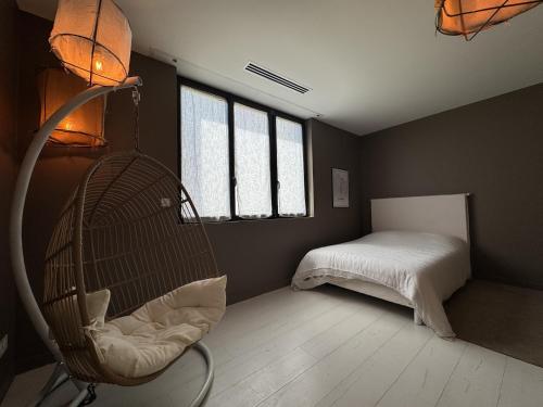 a room with a chair and a bed with windows at Stylish Home Base for Your Adventure in Le Mans