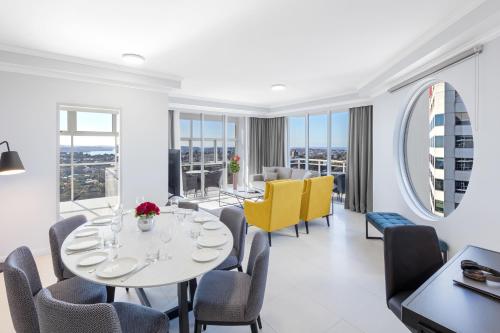 a dining room with a table and chairs and windows at Meriton Suites Bondi Junction in Sydney