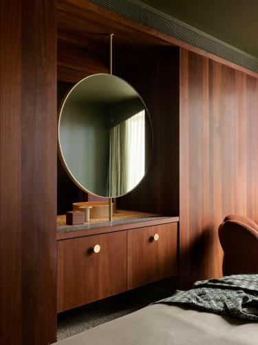 a bedroom with a mirror on a wooden wall at Hyde Melbourne Place in Melbourne