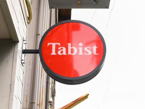 a red and white sign on the side of a building at Tabist Tatsumi Business Hotel Matsusaka in Matsuzaka