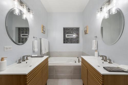 a bathroom with two sinks and a tub and two mirrors at Medical District 2BR with Jacuzzi & Parking in Chicago