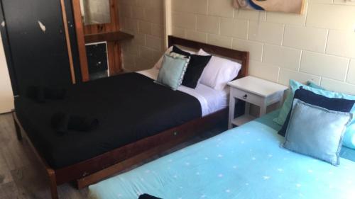 two beds in a room with blue pillows at Mineral Park Motel in Parakai