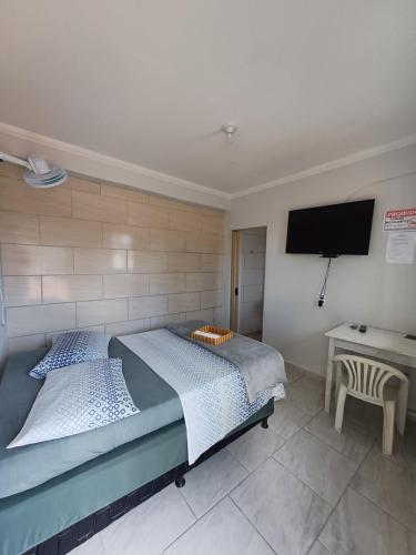 a bedroom with two beds and a flat screen tv at Pousada colina in Cachoeira de Minas