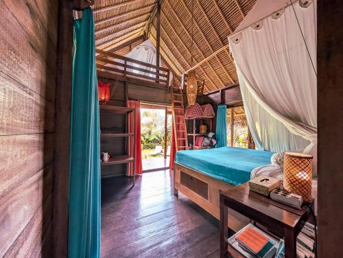 a bedroom with a bed and a table in a room at Cute Eco Cottage Near 7 Waterfalls in Singaraja