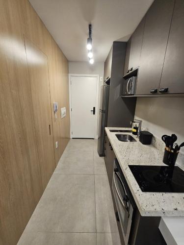 a kitchen with a counter and a sink and a door at Studio Aconchegante - Moema in Sao Paulo