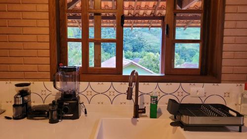 Una encimera de cocina con un fregadero y una ventana. en Casa charmosa no centro de São Pedro da Serra, en Nova Friburgo