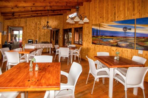 a restaurant with wooden tables and white chairs at Sevens Guesthouse in Kroonstad