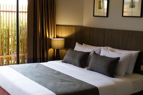 a bedroom with a bed with pillows and a window at Jazzotel Bangkok in Bangkok