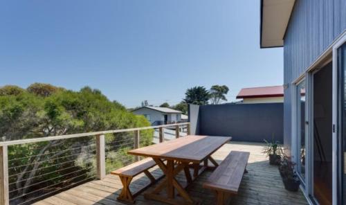 a wooden deck with a wooden table and benches at Murray Street Hideaway in Smiths Beach