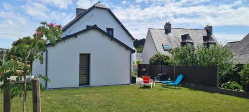 une maison blanche avec une clôture dans la cour dans l'établissement Maison entièrement rénovée, jardin & terrasse à 5min des plages, à Combrit