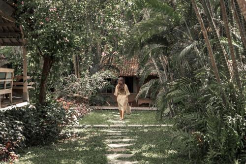 a woman walking down a path in a garden at Balquisse Heritage Hotel in Jimbaran