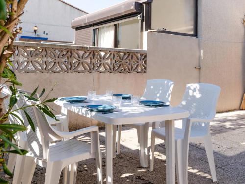 une table et des chaises blanches avec des assiettes et des verres dans l'établissement Villa T3 à Gruissan avec climatisation et jardin - FR-1-409A-36, à Gruissan