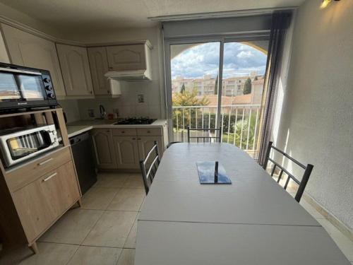 une cuisine avec une table blanche et une grande fenêtre dans l'établissement Studio cabine rénové 4 personnes avec animaux admis - FR-1-749-104, au Cap d'Agde