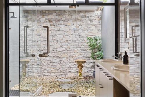 a bathroom with two sinks and a stone wall at Panorama Farm - 3BD Hinterland Hideaway in Bald Knob