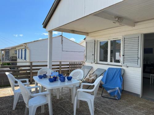 une table blanche et des chaises sur une terrasse dans l'établissement Coquet Chalet à 50m de la Plage - 6 Pers, Terrasse, TV, Lave-vaisselle - FR-1-796-42, à Gruissan