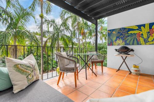 a balcony with a table and chairs and palm trees at Stylish Reef Club 1 BR Apartment in Port Douglas