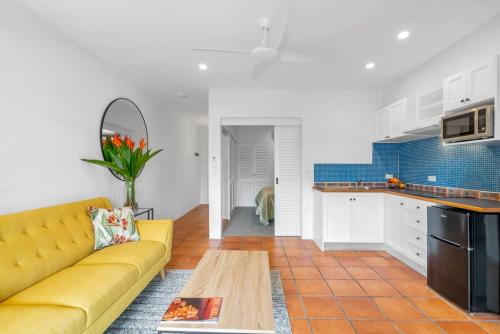 a living room with a yellow couch and a kitchen at Stylish Reef Club 1 BR Apartment in Port Douglas