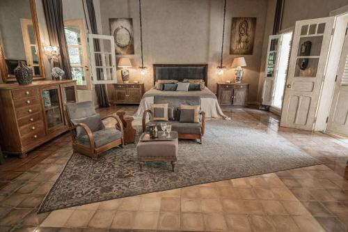 a bedroom with a bed and chairs and a table at Balquisse Heritage Hotel in Jimbaran
