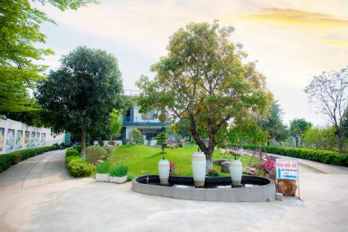 a fountain in the middle of a park with trees at King Bavi Resort in Ba Vì