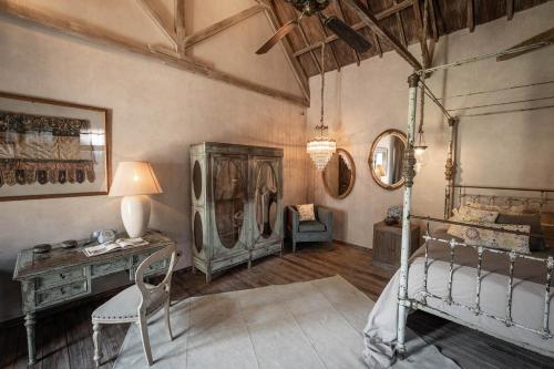 a bedroom with a bed and a desk and a table at Balquisse Heritage Hotel in Jimbaran