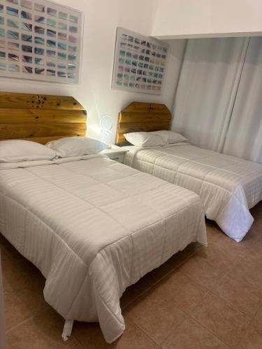 two beds in a hotel room with white sheets at Condo Ocean View from Balcony Swimming Pool Playa Sucia in Cabo Rojo