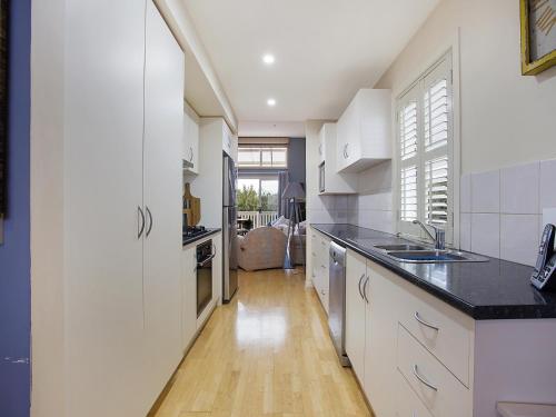 Una cocina con gabinetes blancos y encimera. en Four bedroom beachside apartment, en Warrnambool