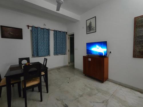 a living room with a table and a tv on a wall at Villa Mariannie in Puducherry