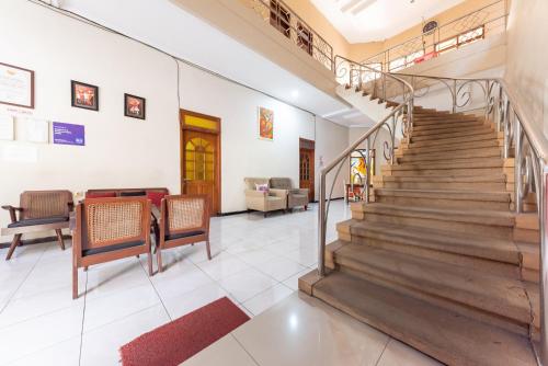 a living room with stairs and a table and chairs at RedDoorz @ Soekarno Hatta Indah in Malang