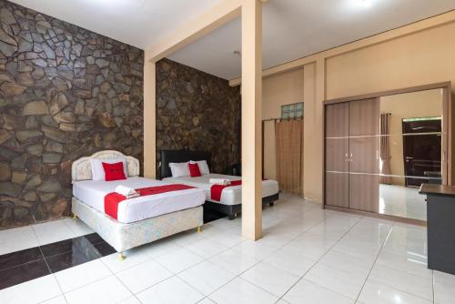 a bedroom with two beds and a stone wall at RedDoorz @ Soekarno Hatta Indah in Malang
