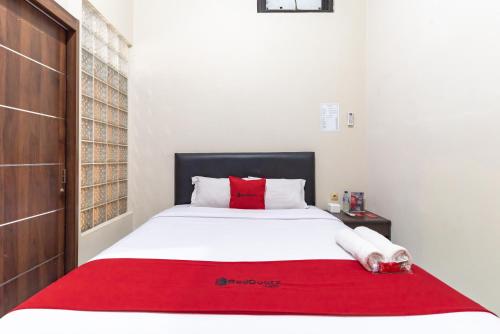 a bedroom with a bed with a red blanket on it at RedDoorz @ Soekarno Hatta Indah in Malang