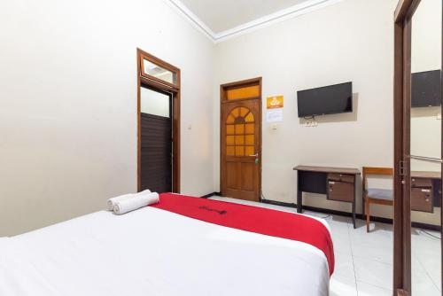 a bedroom with a bed and a desk and a television at RedDoorz @ Soekarno Hatta Indah in Malang