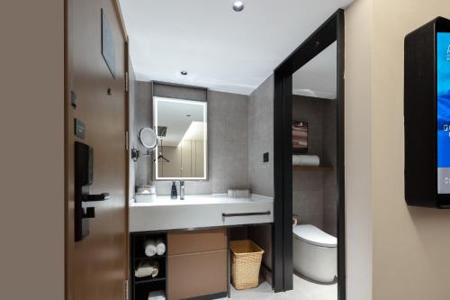 a bathroom with a sink and a mirror and a toilet at Atour Hotel People's Square Metro Station Shanghai in Shanghai