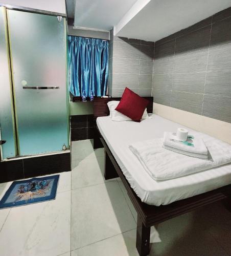 a small room with a bed and a glass shower at KK Hotel - Hostel - 24 hrs Reception in Flat C2 , Tsim Sha Tsui Building, 83-97 Nathan Road, Tsim Sha Tsui, Kowloon in Hong Kong